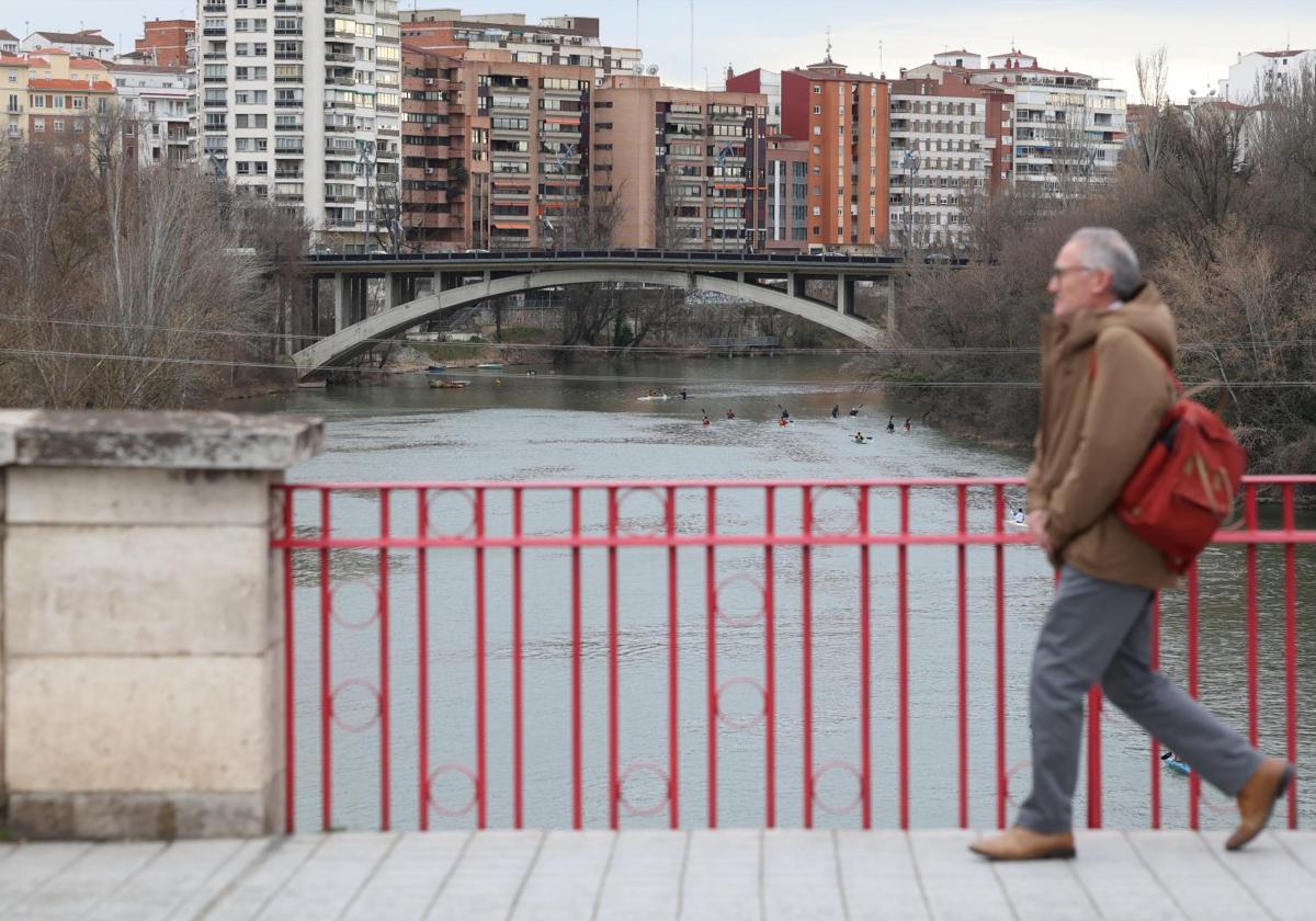 Un hombre camina por el puente de Poniente, sobre el río Pisuerga.
