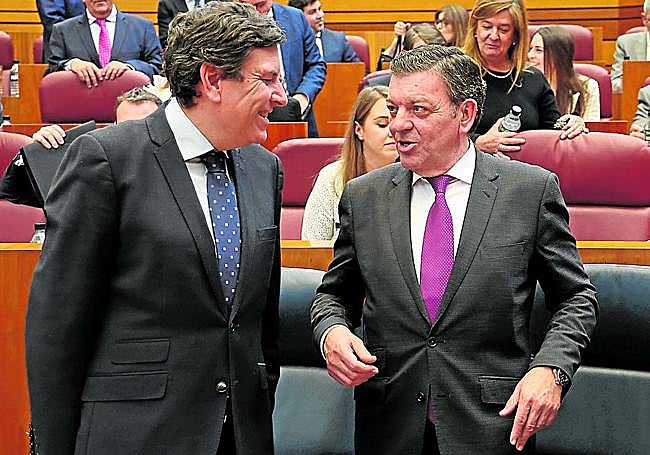 El consejero González Gago (derecha) conversa en las Cortes con su compañero de Economía y Hacienda durante un pleno.