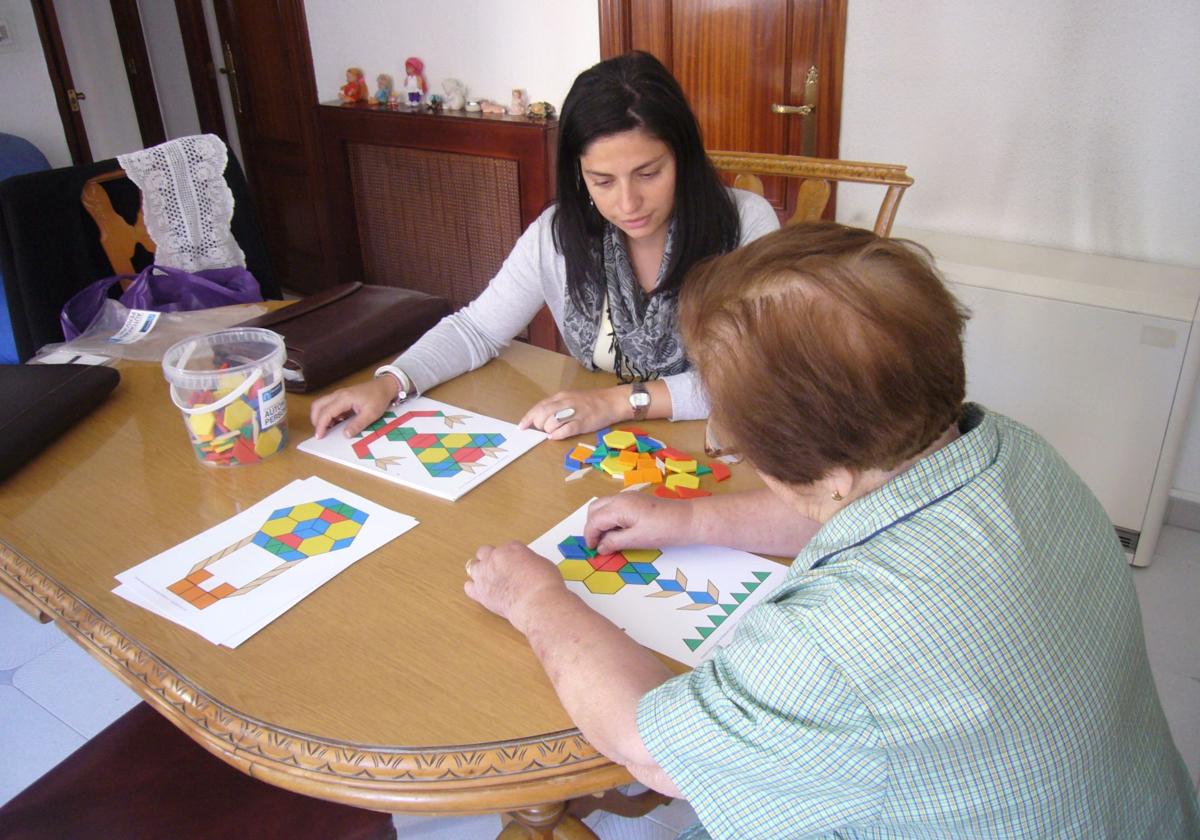 Una usuaria, sobre un juego de lógica con fichas de colores, con la trabajadora que la atiende.