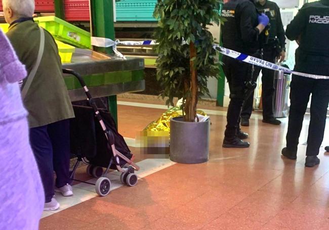 El cuerpo de la víctima, ya tapado, yace bajo el cordón policial mientras otros clientes continuaban con sus compras.