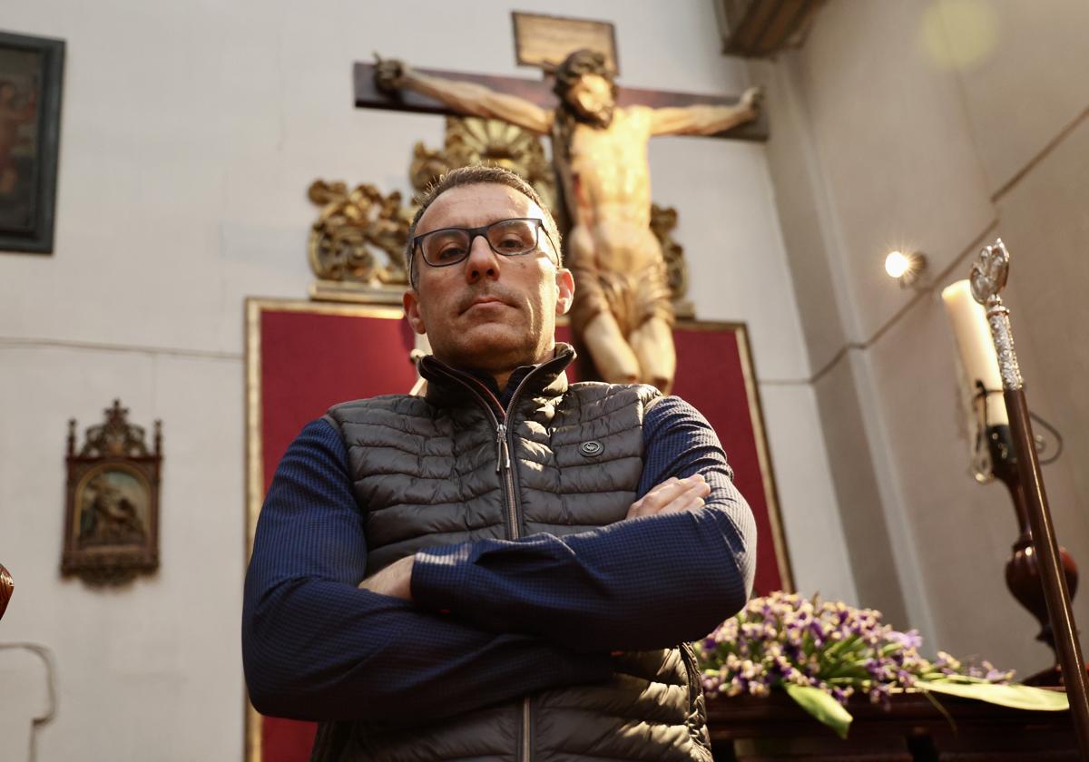 David Flores, secretario en funciones de la Cofradía Penitencial de la Sagrada Pasión de Cristo, posa junto al Cristo de las Cinco Llagas en el interior del templo de San Quirce y Santa Julita.