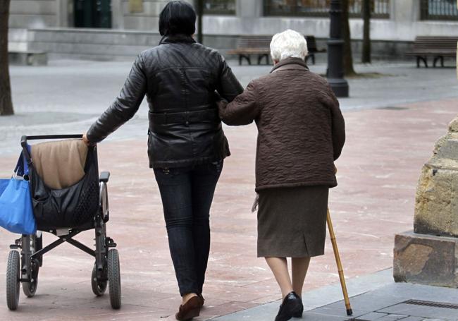 Una mujer mayor pasea acompañada por una calle en una imagen de archivo.