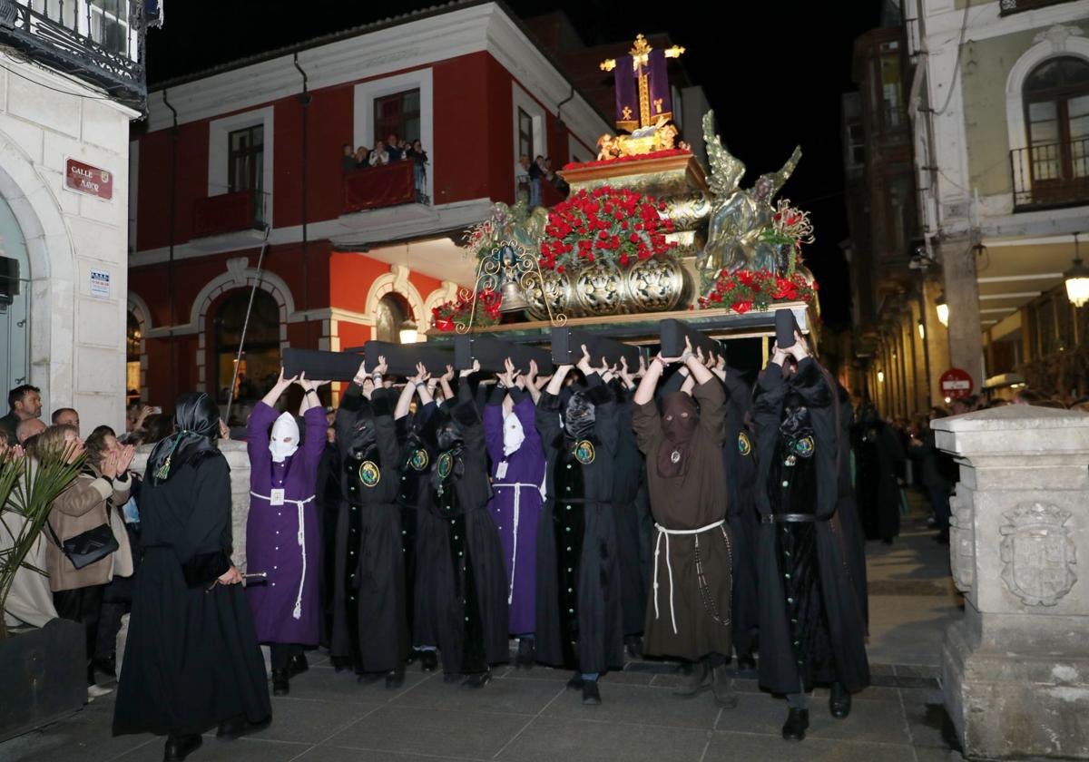 Los cofrades levantan la Vera Cruz para salvar los hitos de piedra de la Calle Mayor.