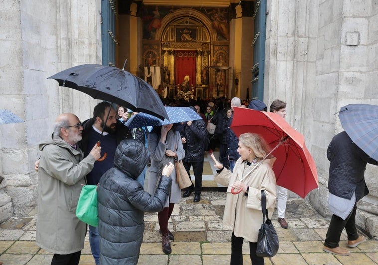 Transeúntes y cofrades comentan la noticia de la suspensión de la Procesión General en la puerta de la iglesia de las Angustias mientras otros aprovechan para visitar las tallas guardadas en su interior