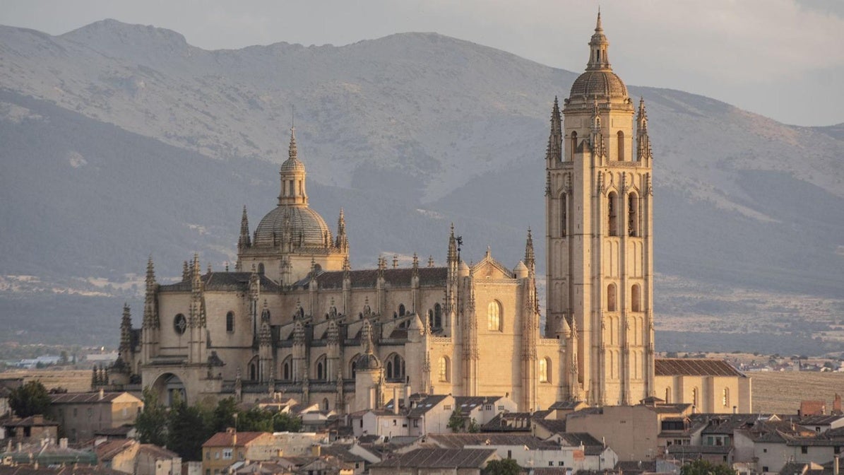 La imponente mole ocre de la Catedral emerge sobre el caserío de la ciudad vieja de Segovia. Al fondo, la sierra de Guadarrama, con la silueta de la Mujer Muerta.