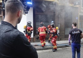 Los bomberos se adrentan en el restaurante, ante la mirada de los empleados.