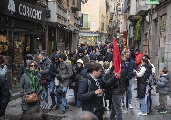 Grupos de turistas circulan por la Calle Real de Segovia este sábado lluvioso y ventoso.