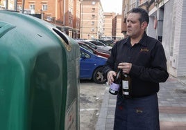 Un hostelero recicla botellas de vidrio en el contenedor al lado de su bar, el Bariloche.