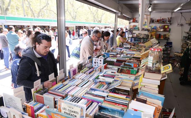 Lectores en una de las casetas de la Feria de Libro Viejo y de Ocasión en la Acera de Recoletos.