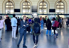 Viajeros en la estación de trenes de Valladolid, con todas las pantallas apagadas.