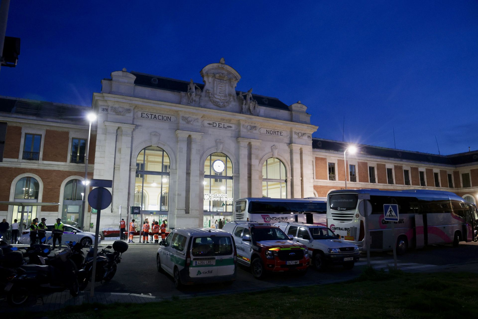Efectivos de las fuerzas y cuerpos de seguridad del estado, miembros de Cruz Roja, taxis y autobuses, en el exterior de la estación de Campo Grande durante la noche del lunes 28 de abril.
