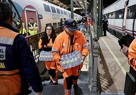 Voluntarios de Protección Civil reparten agua durante el apagón a los viajeros atrapados en la estación de tren de Valladolid.