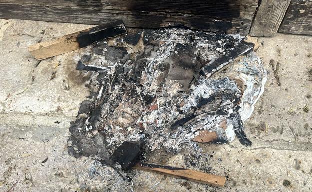 Restos de tablas y cartones prendidos junto a la puerta del Ayuntamiento de Paredes.