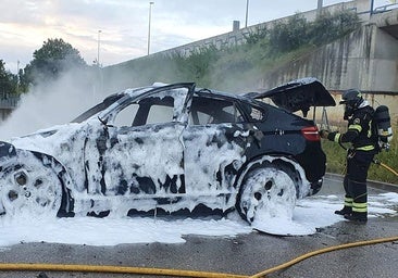 Un bombero de la Diputación remata la extinción del BMW X6 robado y quemado en Arroyo al borde de la VA-30.