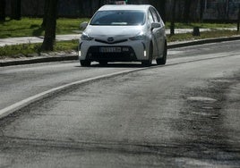Un taxi circula por una carretera en mal estado en Segovia capital.