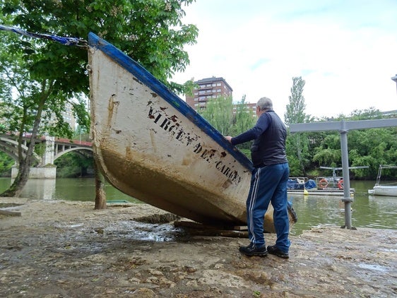 Un voluntario de Los Amigos del Pisuerga examina la barca de la Virgen del Carmen.