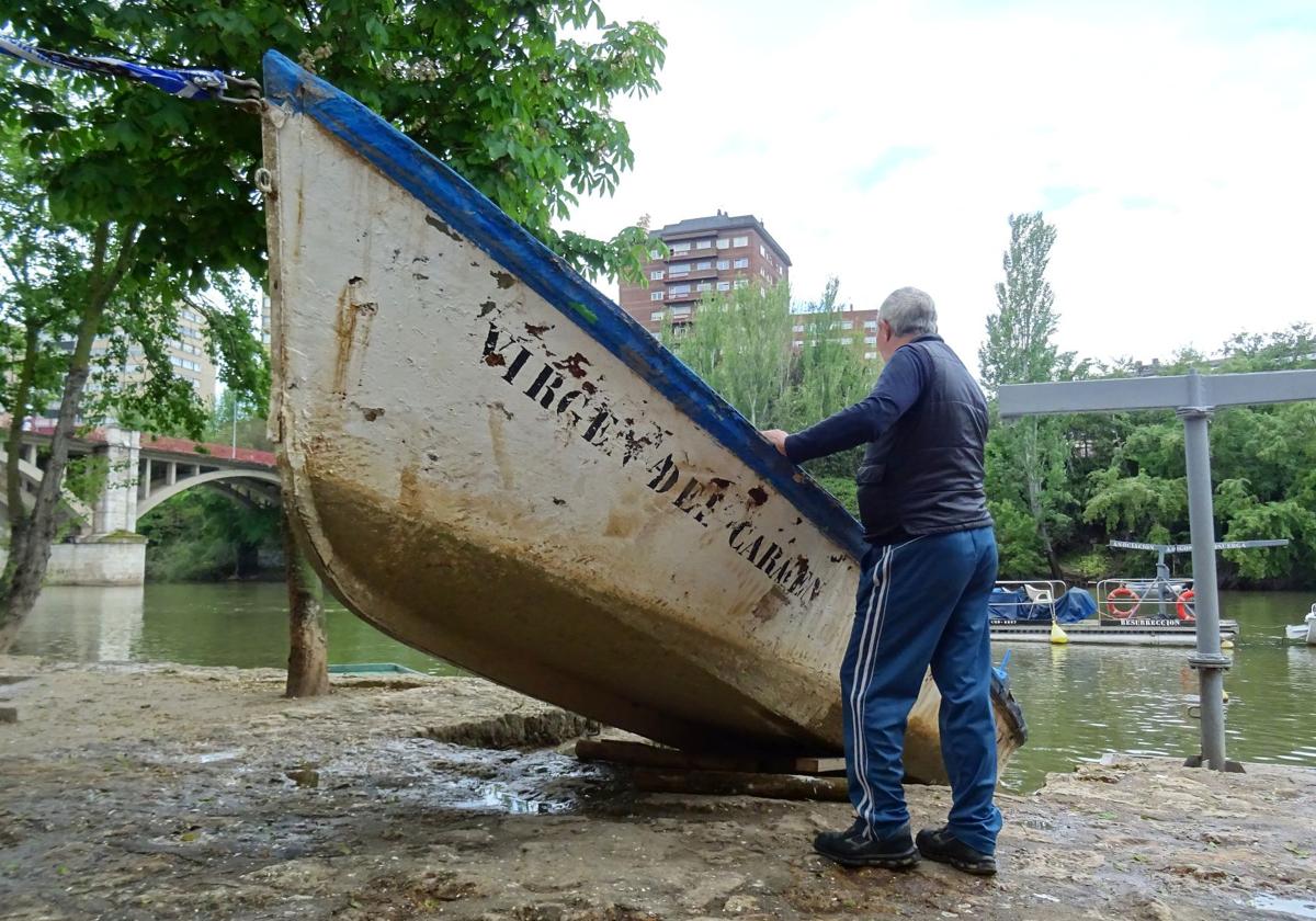 Un voluntario de Los Amigos del Pisuerga examina la barca de la Virgen del Carmen.