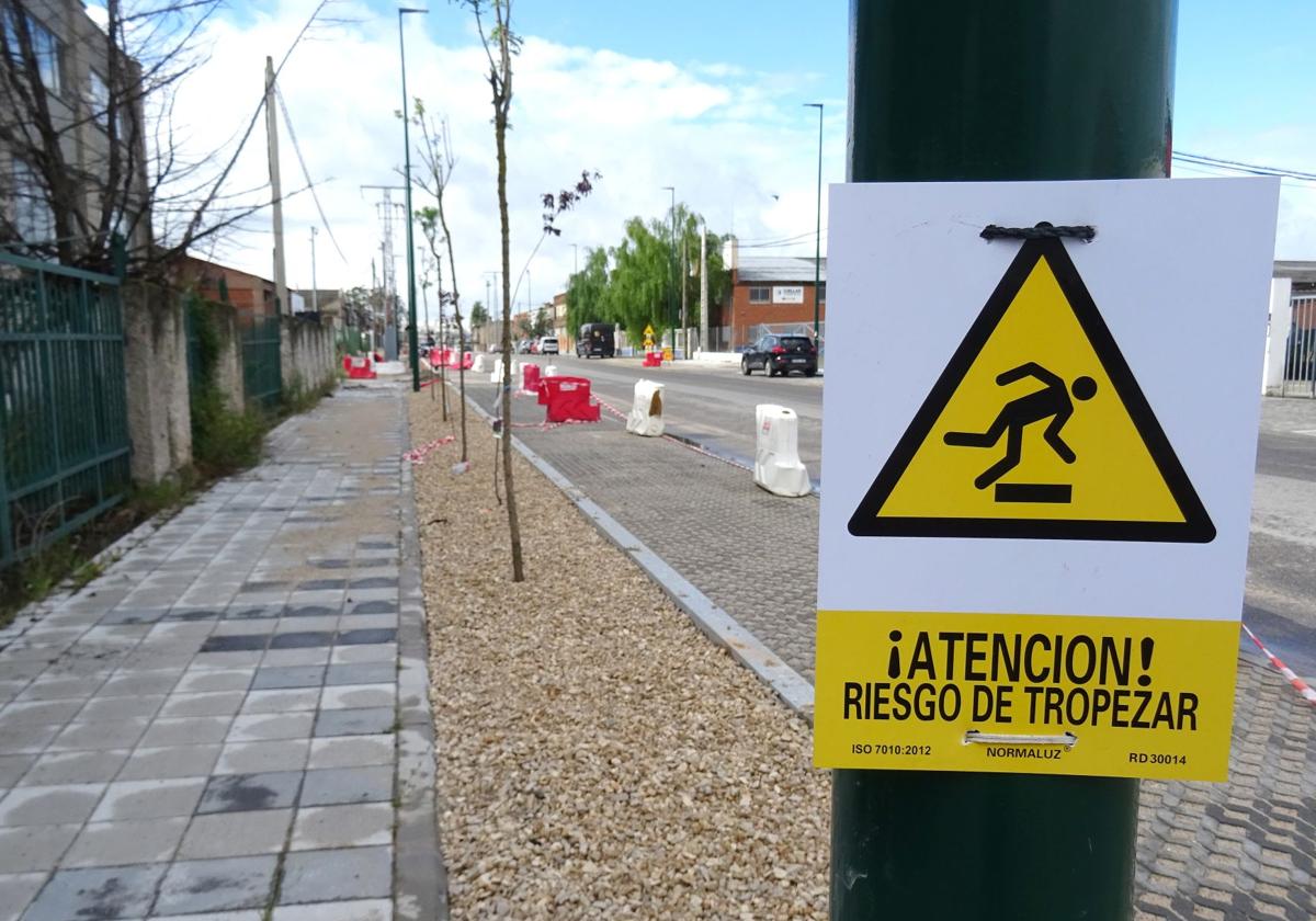 Una llamativa señal advierte a los peatones del riesgo de caídas en la acera adoquinada, pero aún en obras, de la avenida de El Norte de Castilla.