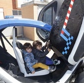 Dos niños disfrutan en uno de los coches de la Policía Local.