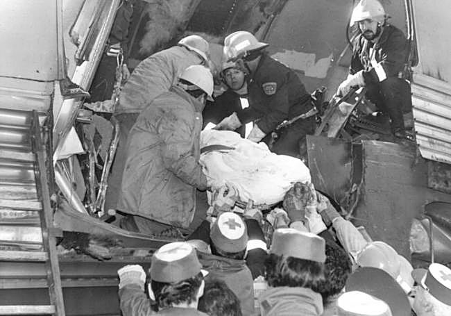 Bomberos y miembros de Cruz Roja sacan el cuerpo de un fallecido en la colisión.