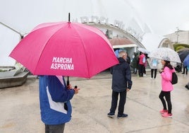 Un participante bajo la lluvia con el paraguas de la Marcha Asprona