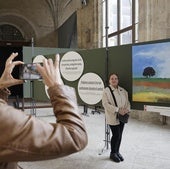 Una mujer toma una foto a Mari Martínez Ramos, autora del cuadro de Pino del Río junto al que posa.