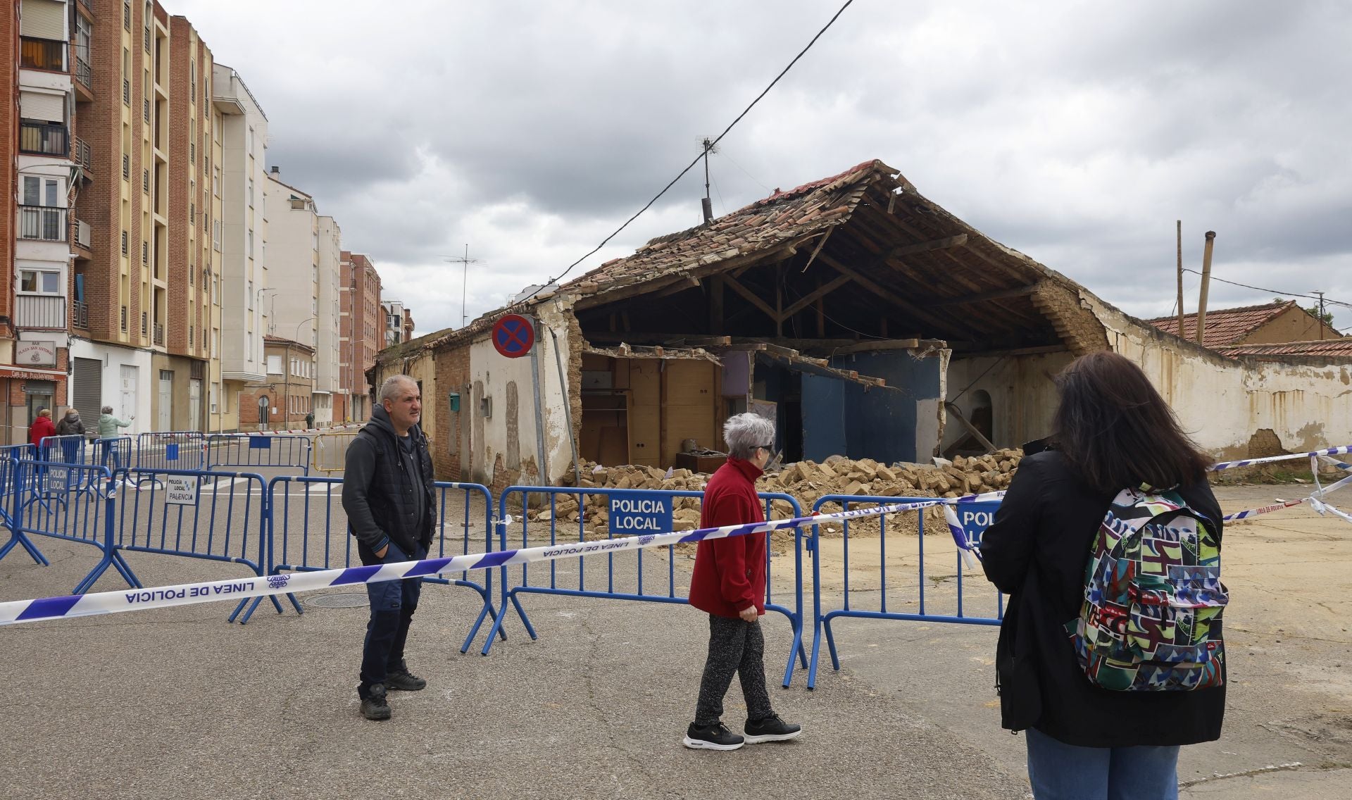 Un grupo de viandantes contempla la vivienda derruida.