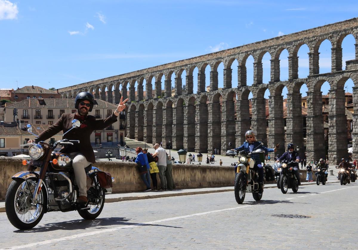 Motoristas vesstidos de traje saludan en su ruta por la ciudad de Segovia.