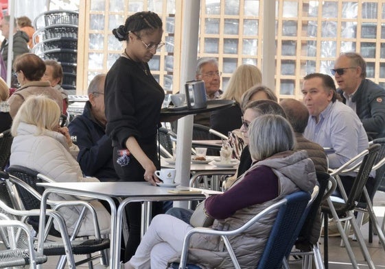 Una camarera sirve a una pareja en una terraza de la Plaza Mayor de Valladolid.