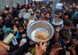 Palestinos reciben comida caliente en un punto de distribución de alimentos en el campamento de refugiados de Nuseirat, en Gaza.