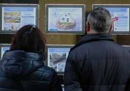 Una pareja observa ofertas de vivienda en el escaparate de una inmobiliaria de Segovia.