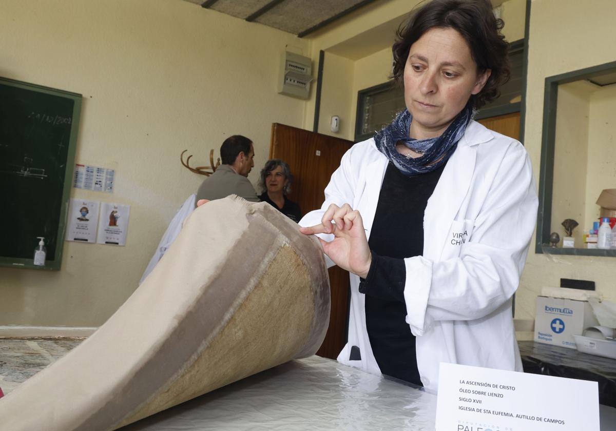 La restauradora Virginia Chacón muestra la trasera de la obra La ascensión de Cristo y la tela suplementada para ajustarla al marco.