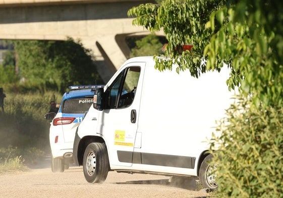 El furgón forense traslada el cuerpo de la víctima escoltado por una patrulla bajo el puente de la VA-30.