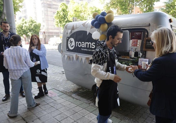 Varias personas se detienen a conocer los servicios de Roams y a tomar un café.