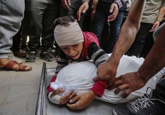 Un niño herido se aferra al cadáver amortajado de un familiar fallecido tras un bombardeo del ejército israelí en Gaza.