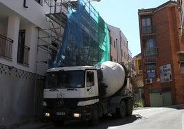 Maquinaria junto a los andamios que cubren un bloque de pisos de reciente construcción.