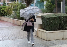 Una mujer se protege de la lluvia y el viento en Palencia, en una imagen de archivo.