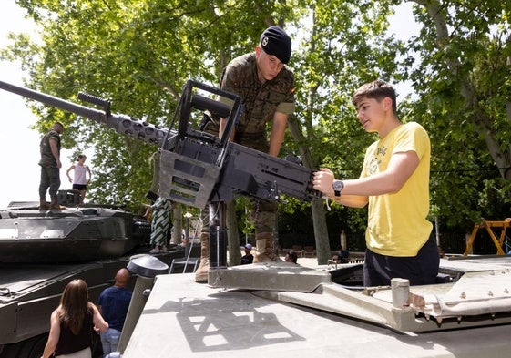 Un joven sujeta el póster de un tanque ante la mirada de un militar.