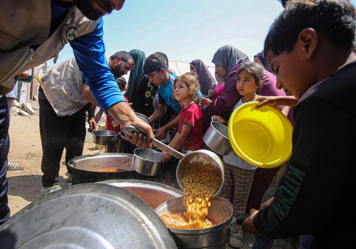 Un grupo de palestinos recibe comida en un punto de distribución en Gaza.