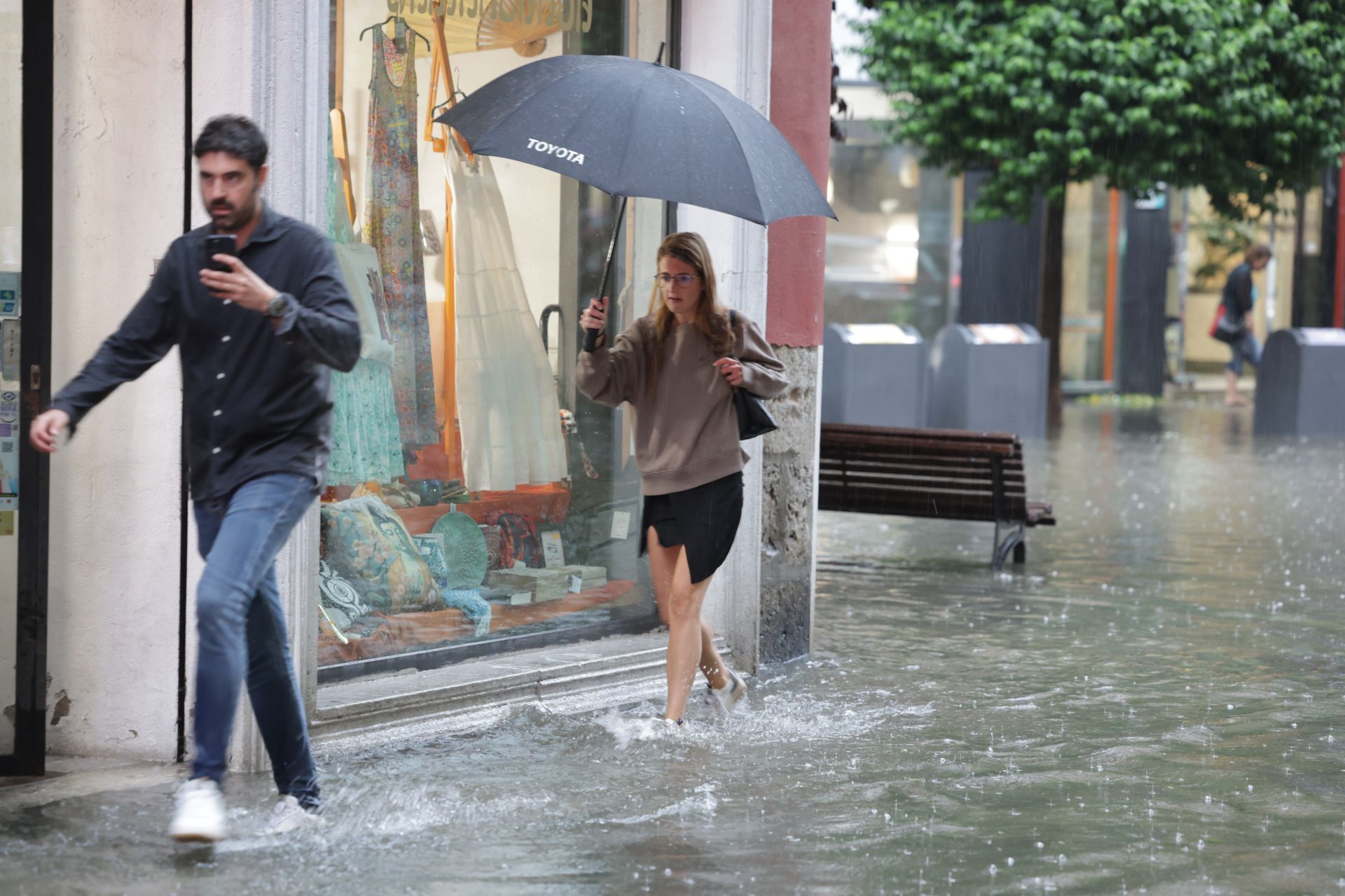 Dos jóvenes caminan por la calle Esgueva en plena tormenta.