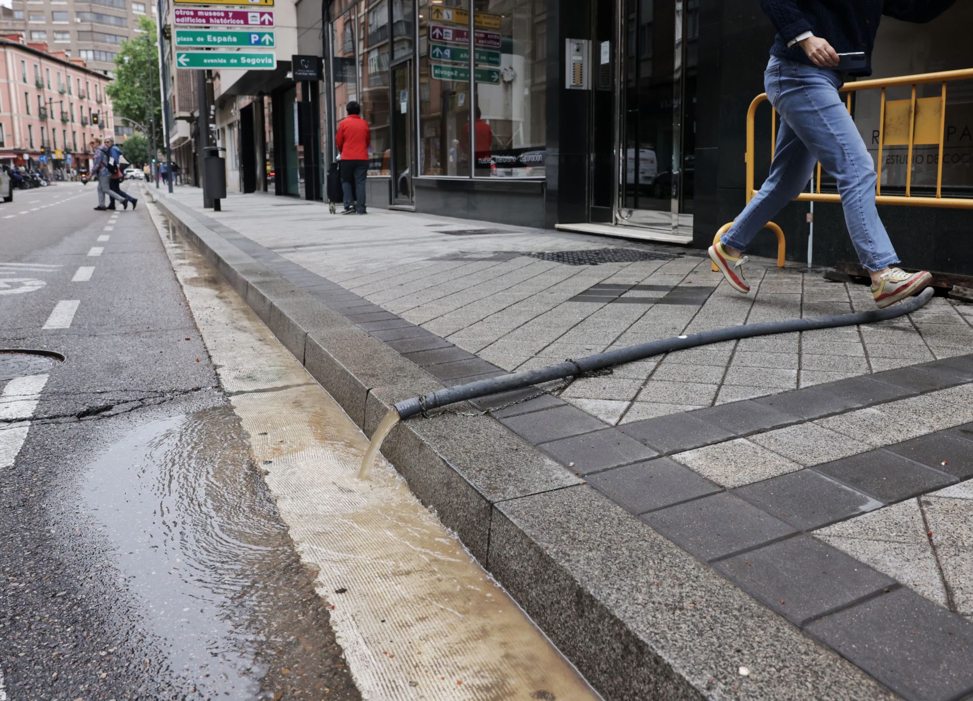 Manguera para achicar agua instalada en un bajo de la calle Nicolás Salmerón.