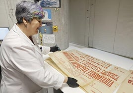 María de los Ángeles Iglesias muestra carteles recién restaurados de partidos de fútbol de los años 20.