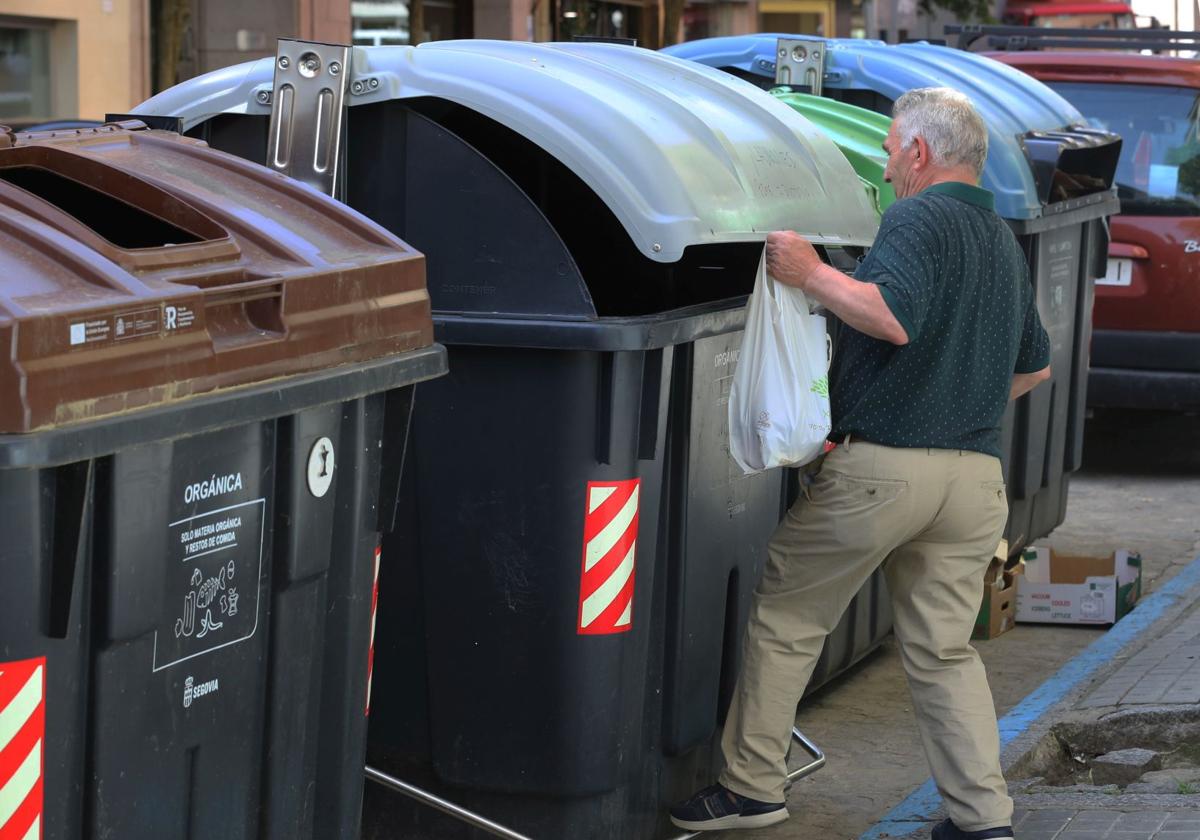 Un vecino deposita una bolsa de basura en un contenedor.