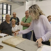 La responsable del Archivo de la Diputación muestra documentos históricos a los visitantes.