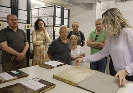 La responsable del Archivo de la Diputación muestra documentos históricos a los visitantes.