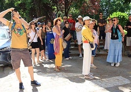 Un grupo de turistas atiende a las explicaciones de una guía en Segovia.