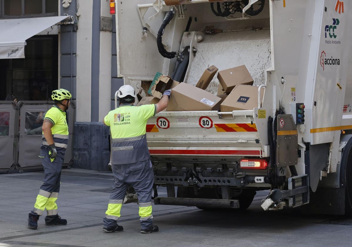 Trabajadores de Palencia Deslumbra recogen basuras de los comercios de la Calle Mayor.