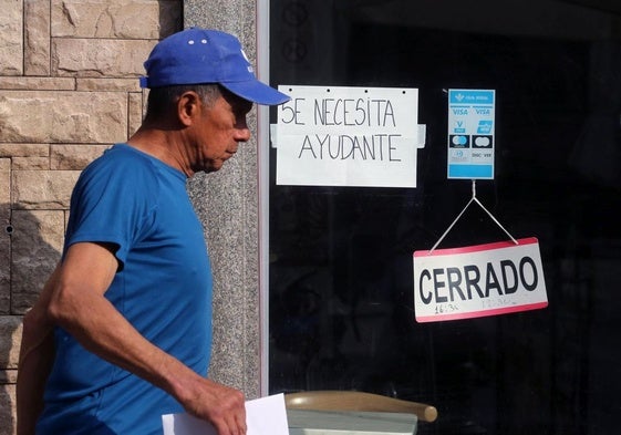 Un hombre pasea junto a un negocio segoviano que busca un trabajador.
