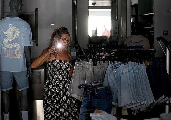 Una mujer con una linterna en una tienda de ropa, el día del apagón.