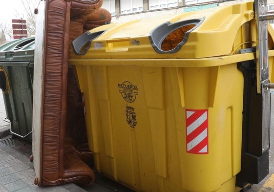 Sofá depositado indebidamente entre dos contenedores en la plaza del Puente.